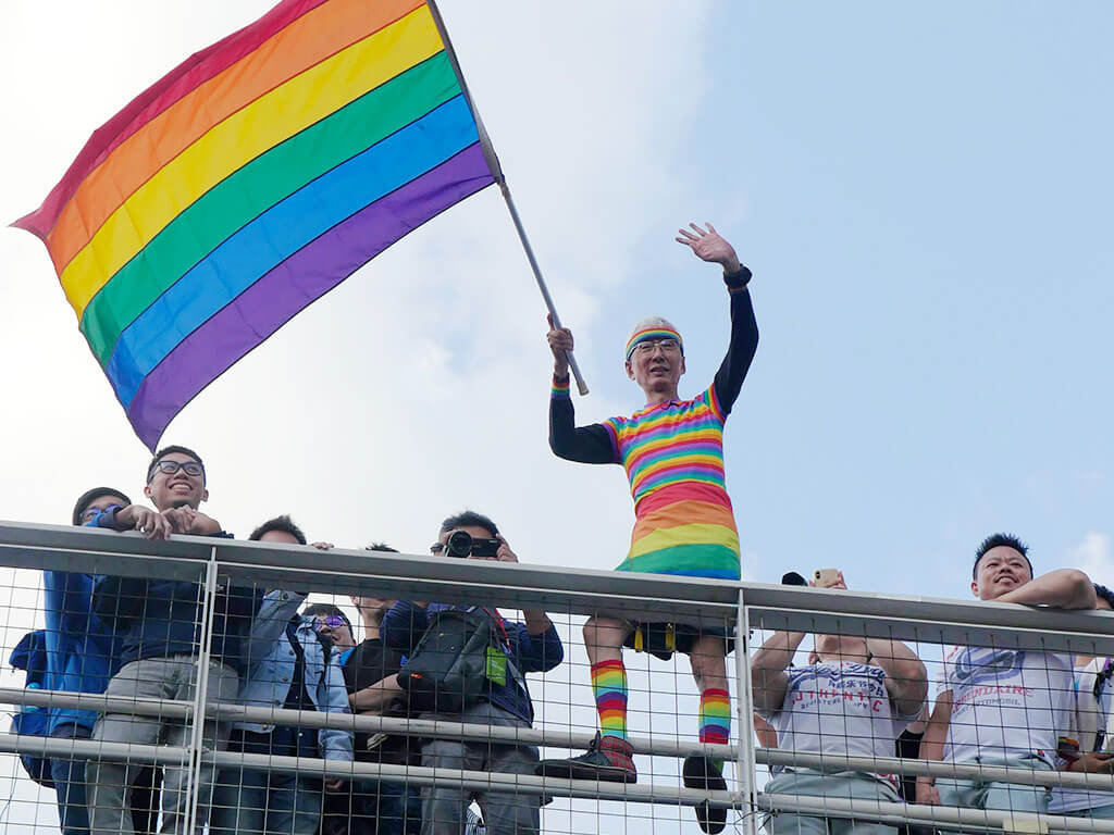 Participants on the pedestrian bridge waved rainbow flags.