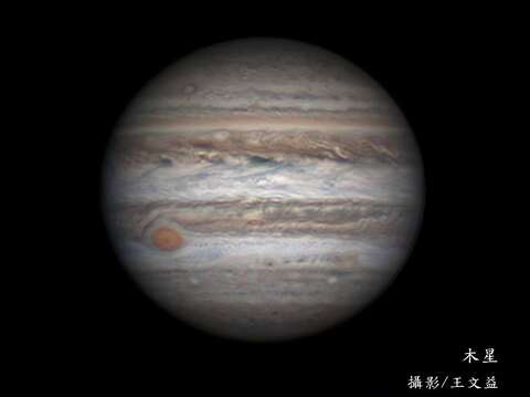 表面充滿斑斕帶紋的木星。左下角即著名的大紅斑，直徑可達數萬公里，為一類似颱風的巨大氣旋風暴。