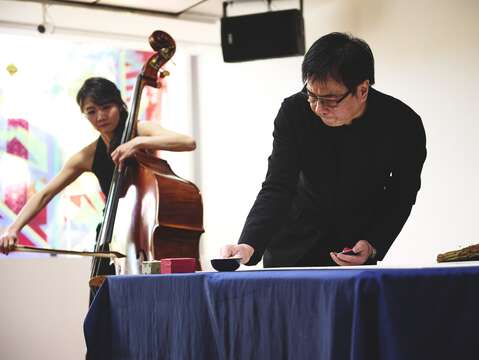 知名書法家暨詩人許悔之使用稻稈現場揮毫，並由國家交響樂團低音提琴手蔡歆婕(圖左)伴奏。