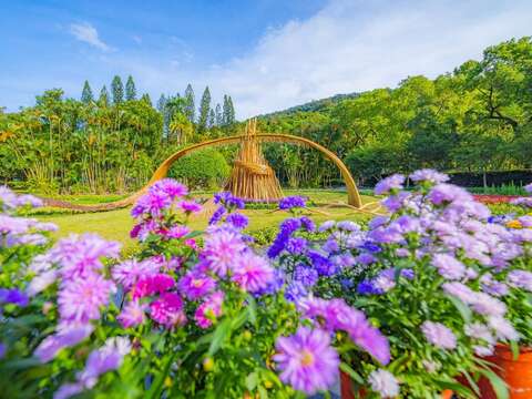 以原木和竹子交融打造的「風起光瀾」與花海交織呈現逐夢旅程的韌性與希望（圖片來源：臺北市政府工務局公園路燈工程管理處）