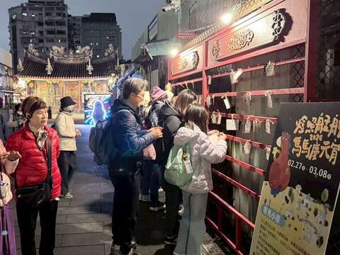 民眾在「燈照艋舺：馬馬慶元宵」活動許願牆綁上許願卡，祈求平安與心願成真。（圖片來源：臺北市政府觀光傳播局）