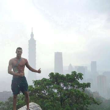 匈牙利游泳選手冒著細雨登象山，興奮地脫去上衣與臺北101合影留念。