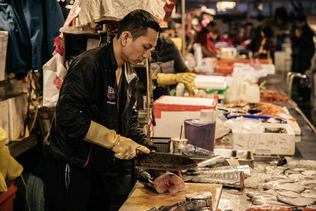 用专注的神情和熟练的刀法分切鲜鱼，是鱼市场的日常风景。