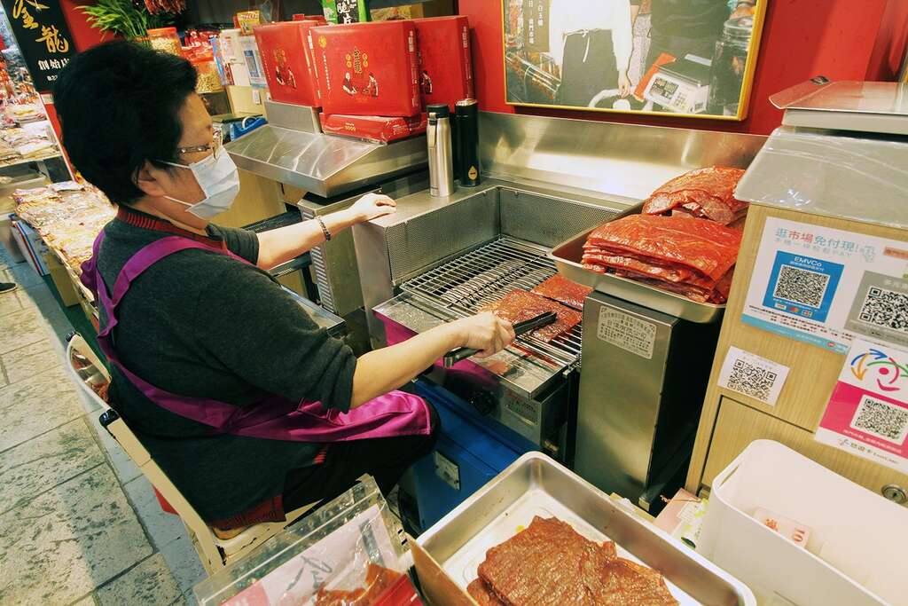 金龍肉乾創始店老闆娘白玉嬌半世紀以來堅守崗位,在攤位前為客人烤出一片片令人驚艷的好吃肉乾