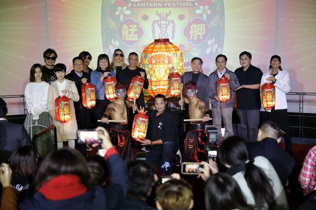 2021台北燈節卡司陣容及出席貴賓合影，左起白安、魏嘉瑩、董事長樂團、臺北市萬華區區長詹天保、臺北市政府觀光傳播局副局長李麗珠、策展藝術家李明道Akibo老師、臺北市政府副市長蔡炳坤、臺北市政府副秘書長簡哲宏、臺北市政府觀光傳播局局長劉奕霆、Jamii Szmadzinski、前排九天民俗技藝團，臺北市觀光傳播局提供）