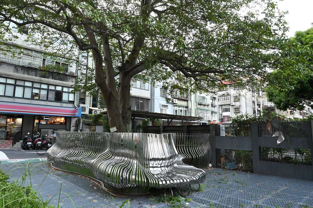 老樹與不鏽鋼藝品相輔相成，為城市塑造了一處舒心角落。（攝影／ Vivienne Lin）