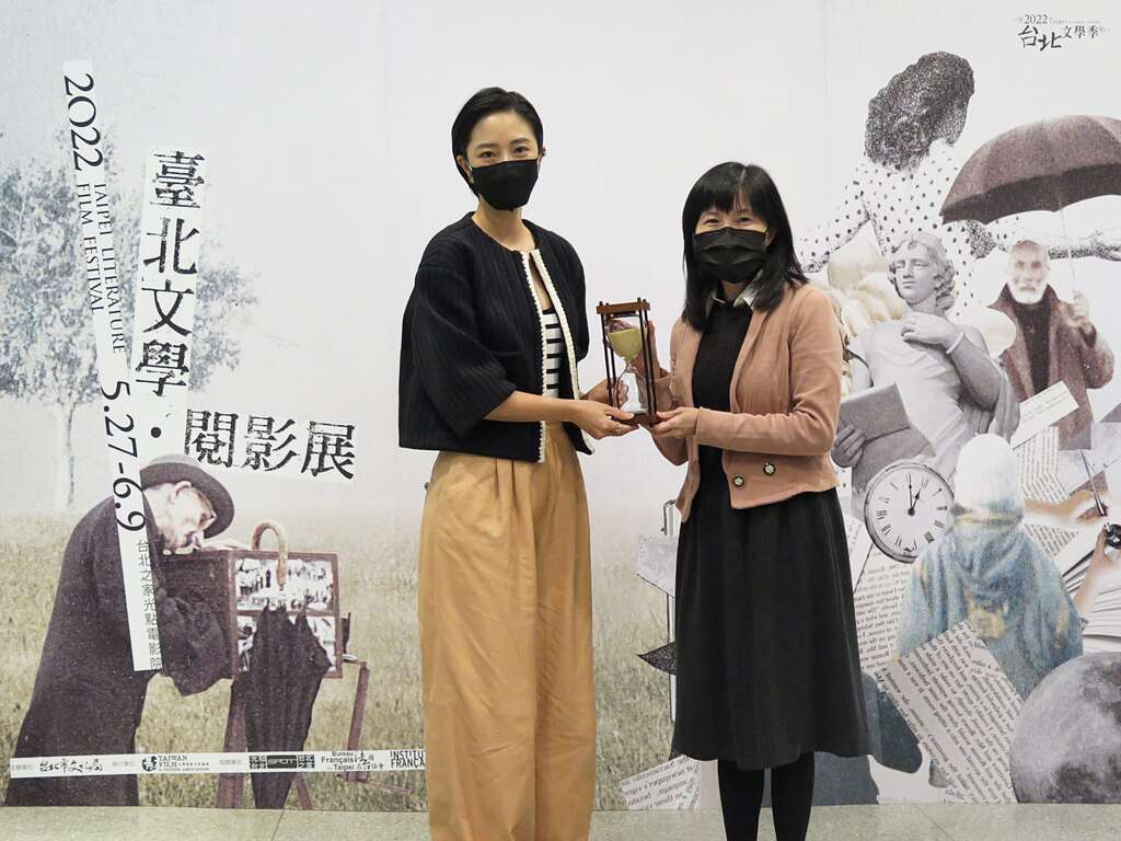 【0504臺北文學．閱影展記者會】文化局副局長陳譽馨遞沙漏給影展嘉賓桂綸鎂，象徵影展主題時間的記憶