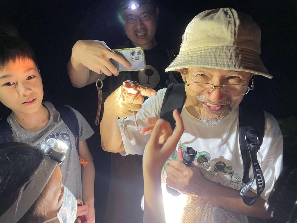 富陽公園蛙調志工郭水源老師在讓小朋友們輪流體驗蛙類吸盤的黏著力，接著示範如何將斑腿樹蛙裝入網袋，進行移除外來種的作業。(圖片來源：臺北市政府觀光傳播局)