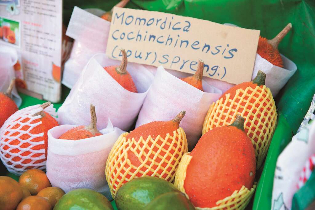 1-3蔬果摊老板娘特意制作木鳖果的英文说明牌，让外籍顾客也能一目了然。