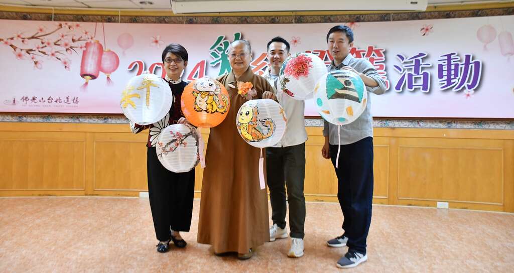 佛光山台北道场住持满谦法师拿着自己的彩绘灯笼作品与民众合照(图片来源：佛光山台北道场)