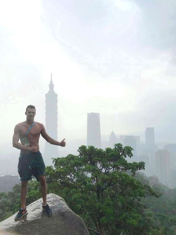 匈牙利游泳选手冒着细雨登象山，兴奋地脱去上衣与台北101合影留念。