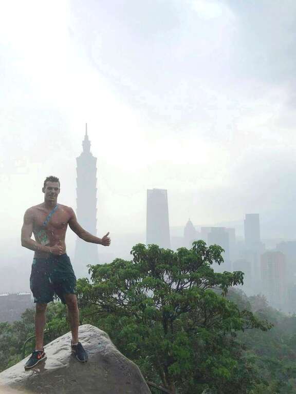 匈牙利游泳選手冒著細雨登象山,興奮地脫去上衣與臺北101合影留念。