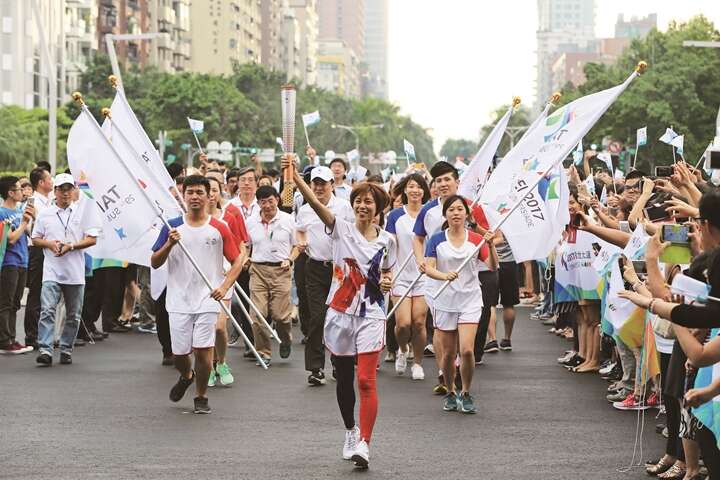 Chen Shih-hsin, Olympic gold-medal winner in taekwondo, carries the torch to its platform at Taipei City Hall, proudly holding it aloft.